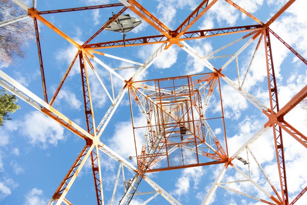 Radiomasto alhaaltapäin kuvattuna pilvistä taivasta vasten.