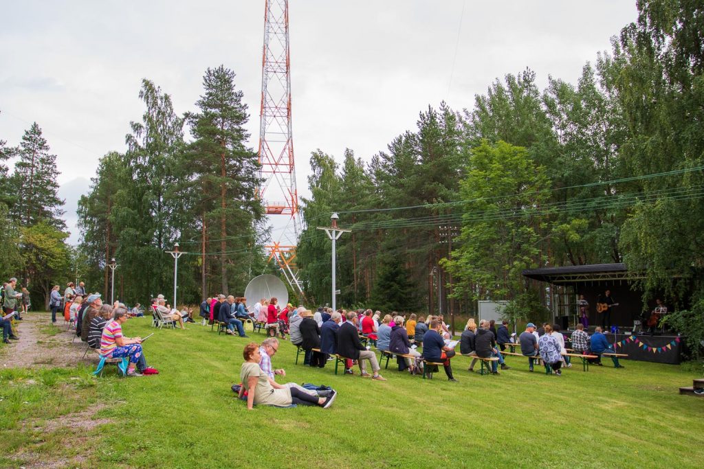 Ihmisiä yhteislauluillassa Mastolan pihalla.