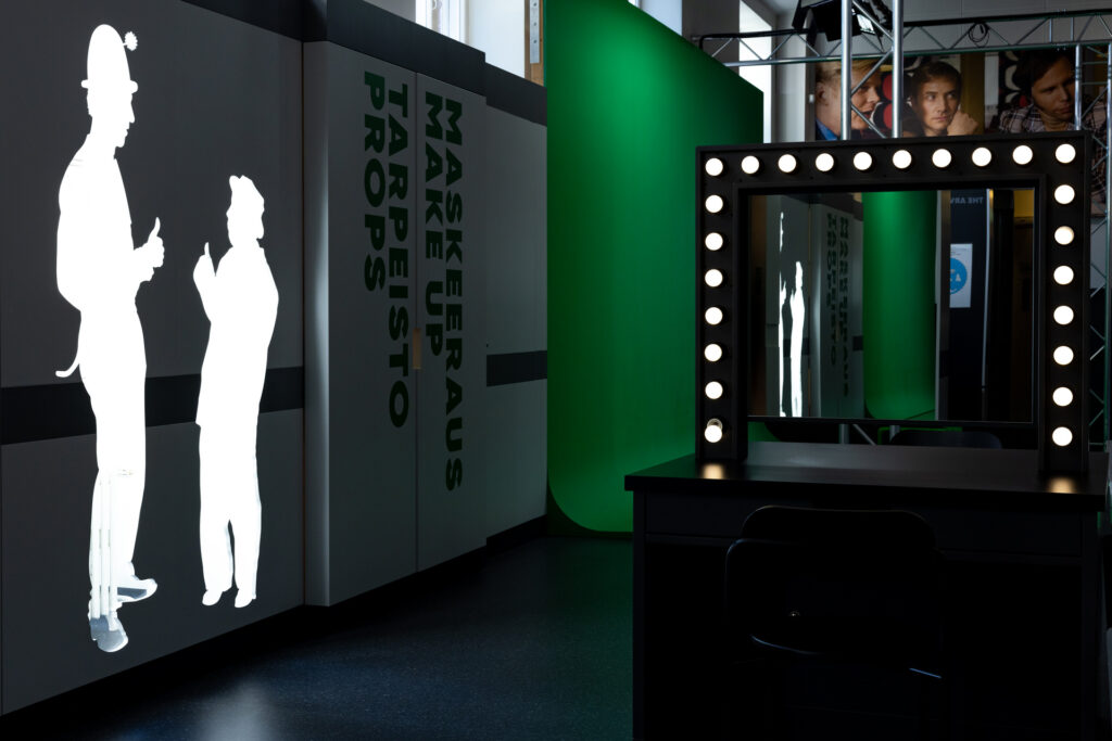 A general view of the museum interior, with a make-up table and a prop cabinet. In the background, Mastola's green screen studio, which is available for use by customers, can be seen.
